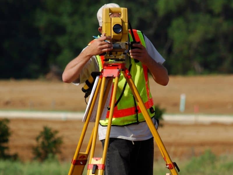 Land surveyor using a total station before planning improvements on an older property